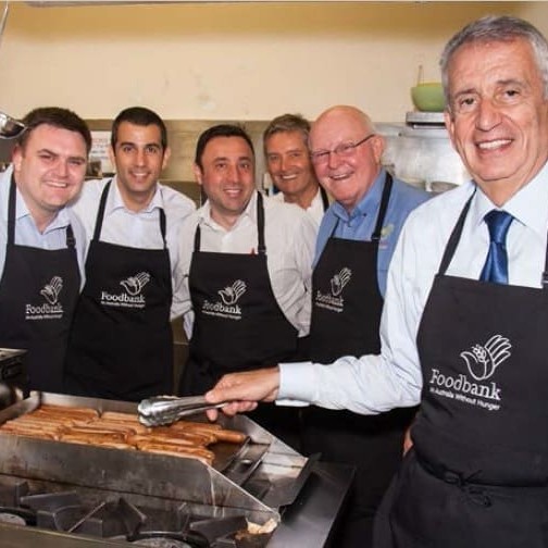 Primo CEO Paul Lederer (right), prepares the snags for lunch at William Booth House, with (from left) Bernie McNally and Rob Lederer from Primo, Nick Pavia from Devro, Geoff Starr and Gerry Andersen from Foodbank.