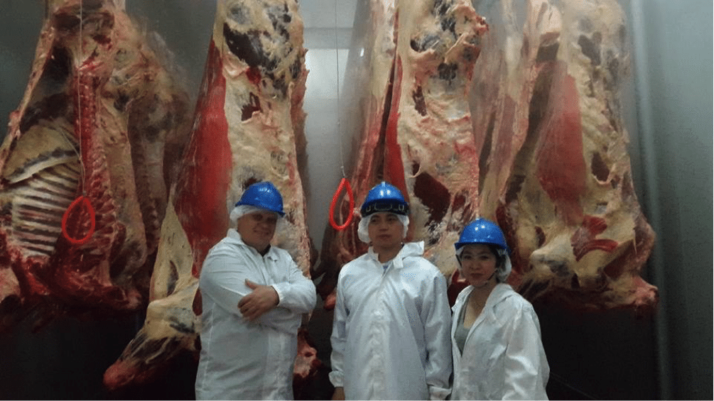 David Tea (centre) with journalist Darren Gall and David’s wife Alyssa Chao in the chiller of their new abattoir in southern Cambodia. The bodies are from the first shipment of Australian cattle which arrived last month.