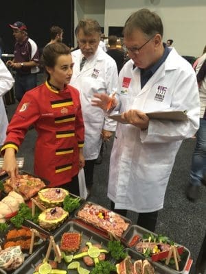 Judges quiz a UK apprentice about features of her retail presentation in the apprentice's competition